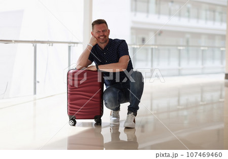 Happy smiling man is sitting suitcase in hotel Happy smiling man is sitting suitcase in hotel 107469460