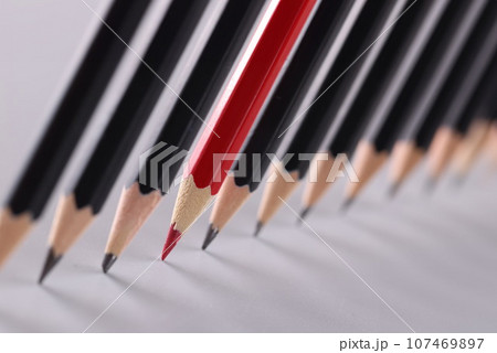 Red pencil separating row of black pencils 107469897