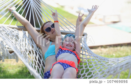 Loving family mom and daughter spend time together in summer hammock Loving family mom and daughter spend time together in summer hammock 107469898
