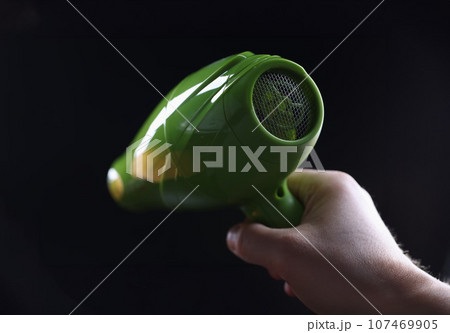 Person holds hair dryer back view and shows metal mesh covering inside of device Person holds hair dryer back view and shows metal mesh covering inside of device 107469905