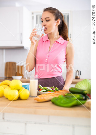 Woman drinks water in the kitchen before breakfast 107470749