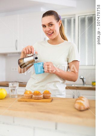 Cheerful woman drinking coffee in apartment 107470758