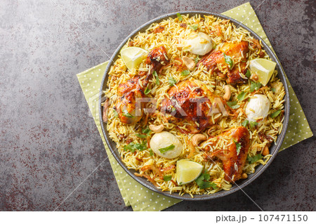 Chicken pulao or Polao with fried onion, egg, nut and raisins closeup on the plate. Horizontal top view 107471150