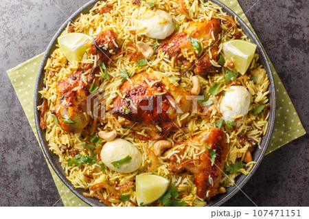 Festive pilaf Morog Polao made from chicken and spicy basmati rice with boiled eggs and fried onions closeup on the plate. Horizontal top view 107471151