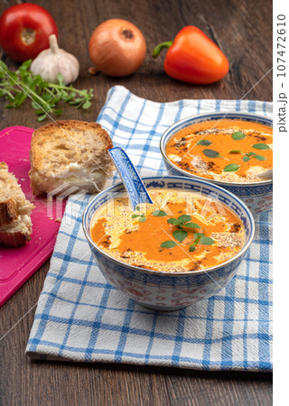 Plates with tomato cream soup on a kitchen towel and toast with soft cheese. Plates with tomato cream soup on a kitchen towel and toast with soft cheese. 107472610