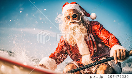 A modern tanned older man in a Santa Claus costume rides a surfboard for swimming. Winter holidays, New Year, Christmas 107473386