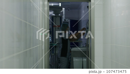Surgeon comes to operating room and puts on lab coat 107473475