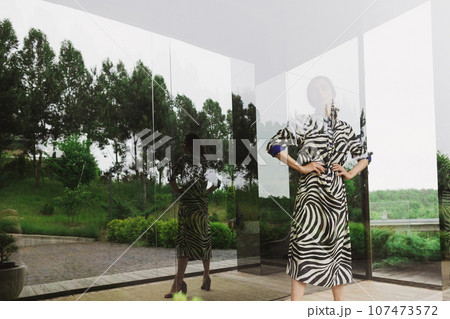 High fashion photo of a beautiful elegant young woman in a pretty zebra print dress posing outdoor. Slim figure High fashion photo of a beautiful elegant young woman in a pretty zebra print dress posing outdoor. Slim figure 107473572
