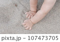 Baby enjoying putting his hands in sand at a beach. 107473705