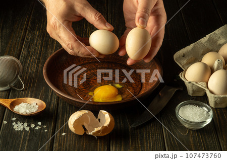 Egg breakfast by the hands of the chef in the kitchen of the restaurant. The process of cooking eggs on the kitchen table. Healthy eggs diet. Egg breakfast by the hands of the chef in the kitchen of the restaurant. The process of cooking eggs on the kitchen table. Healthy eggs diet. 107473760