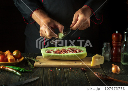 The chef adds onions to the marrow. The concept of cooking national stuffed squash or zucchini in the restaurant kitchen 107473778