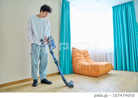 Young guy doing vacuuming at home Young guy doing vacuuming at home 107474058