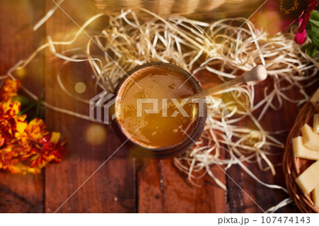 a jar of sweet honey in a bucket on a wooden table in the garden with flowers for breakfast delicious food. High quality photo 107474143