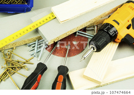 tools for repair and construction. Screwdriver, furniture screws, measuring tape, self-tapping screws, with a place for text. Top view 107474664