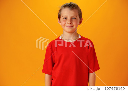 Smiling teen boy in red T-shirt against yellow background 107476160