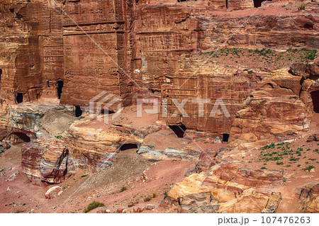 View of the Temples and caves carved into the sandstone rock in the gorge. Petra, Jordan View of the Temples and caves carved into the sandstone rock in the gorge. Petra, Jordan 107476263