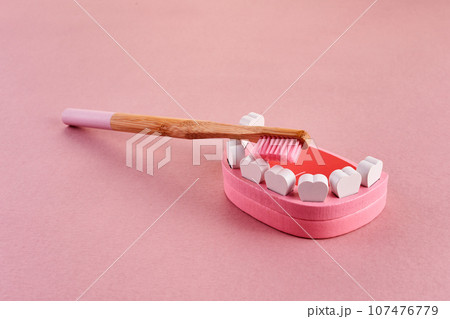 National brush day. Tooth with toothbrush on pink background. Dental health concept. National brush day. Tooth with toothbrush on pink background. Dental health concept. 107476779