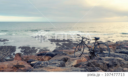 An aged bicycle by the rocky seashore. Concept of loneliness, remoteness and time. 107477713