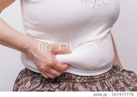 【お腹の肉を摘む主婦】 107477779