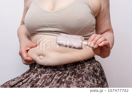 【お腹の肉を摘む主婦とでべそ　アイス】 107477782