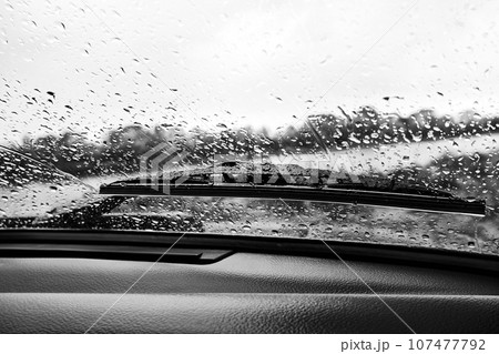 Raindrops on the windshield of a car, view from the inside. Black and white photo 107477792
