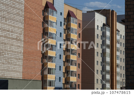 Facade of multi-storey buildings with windows and balconies. 107478615