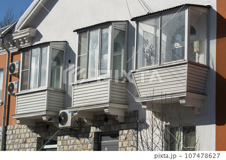 Three glazed balconies on the facade of a two-story building. 107478627