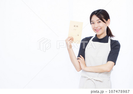 白い背景の前に立ち給料袋を持つ30代の主婦 107478987