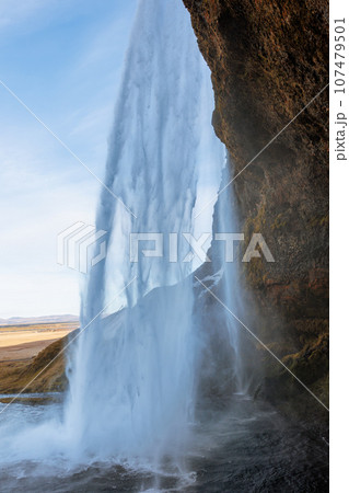 Inside arctic skgafoss waterfall with river stream frunning down off mountain edges, icelandic cascade with water flow falling. Scandinavian nature and wilderness, beautiful landscape. 107479501