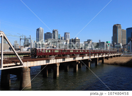 ビル群と淀川を渡る阪急電車 107480458