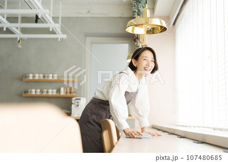 テーブルを拭くカフェの店員 107480685