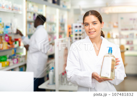 Portrait of a smiling young female pharmacist, demonstrating recently received goods for sale 107481832