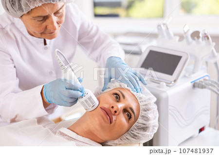Young woman experiencing facial cryotherapy procedure using ice hammer Young woman experiencing facial cryotherapy procedure using ice hammer 107481937