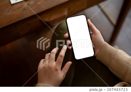 Close-up image of a woman using her smartphone while sitting in a coffee shop. chat, message, apps Close-up image of a woman using her smartphone while sitting in a coffee shop. chat, message, apps 107483723