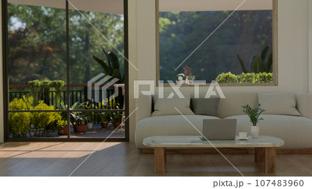 Interior design of a modern minimalist home living room with a balcony with green garden. 107483960