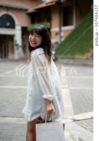 A pretty Asian woman is carrying her shopping bags and enjoying her shopping day in the city. 107484137