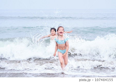 A boy and a girl are having fun playing in the sea. 107484155