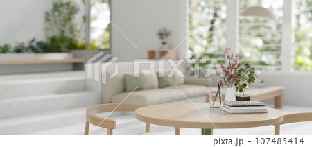 Close-up image of a wooden table with a wooden chair in a modern spacious bright living room. 107485414