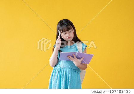 A thoughtful and cute young Asian schoolgirl is focusing on reading a book. thinking, confused 107485459
