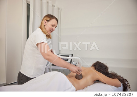 professional equipment, receiving massage, Applying vacuum. Massage of body with vacuum, problem areas slimming using professional equipment, lpg massage, anti-cellulite roller-vacuum massages 107485807