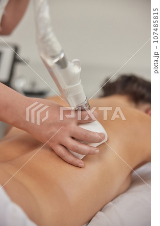 microdermabrasion equipment, massage procedure, weight loss. Young woman with body shaping machine, masseur massages client with vacuum roller, figure correction massage anti-cellulite massage 107485815