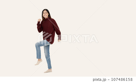 A joyful Asian woman stands against an isolated white background in a cheerful full-body pose. 107486158