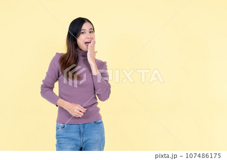 A cheerful Asian woman is covering her mouth, saying wow, surprised by unexpected news A cheerful Asian woman is covering her mouth, saying wow, surprised by unexpected news 107486175