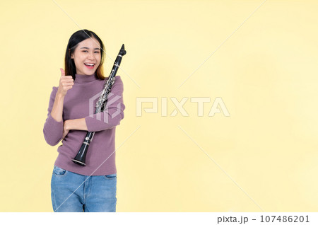 A beautiful and talented Asian woman holding a clarinet and showing her thumb up 107486201