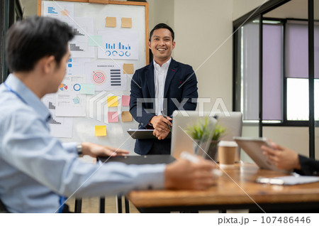 A professional Asian businessman presented his project in front of board members in a meeting 107486446