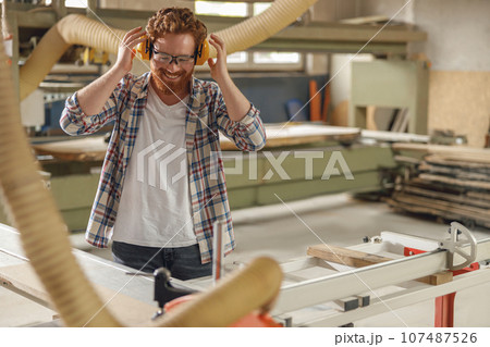 Professional carpenter cutting wooden board at sawmill carpentry manufacturing . Sawing machine Professional carpenter cutting wooden board at sawmill carpentry manufacturing . Sawing machine 107487526