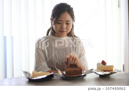どのケーキを食べるか悩む女性 107489862