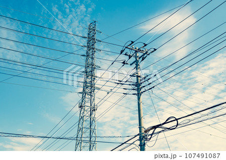 交差する高圧送電線と住宅街の電線と秋の空　暖色加味 107491087