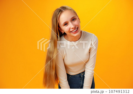 Photo of teen girl smiling portrait against yellow background in studio 107491312