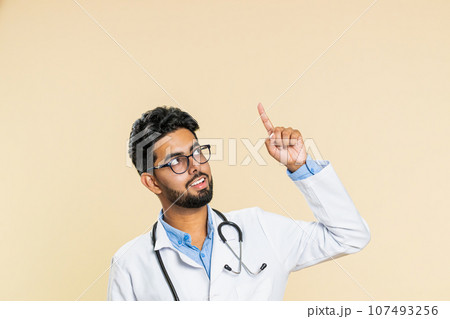Doctor man showing thumbs up and pointing on blank space place for advertisement promotion logo Doctor man showing thumbs up and pointing on blank space place for advertisement promotion logo 107493256